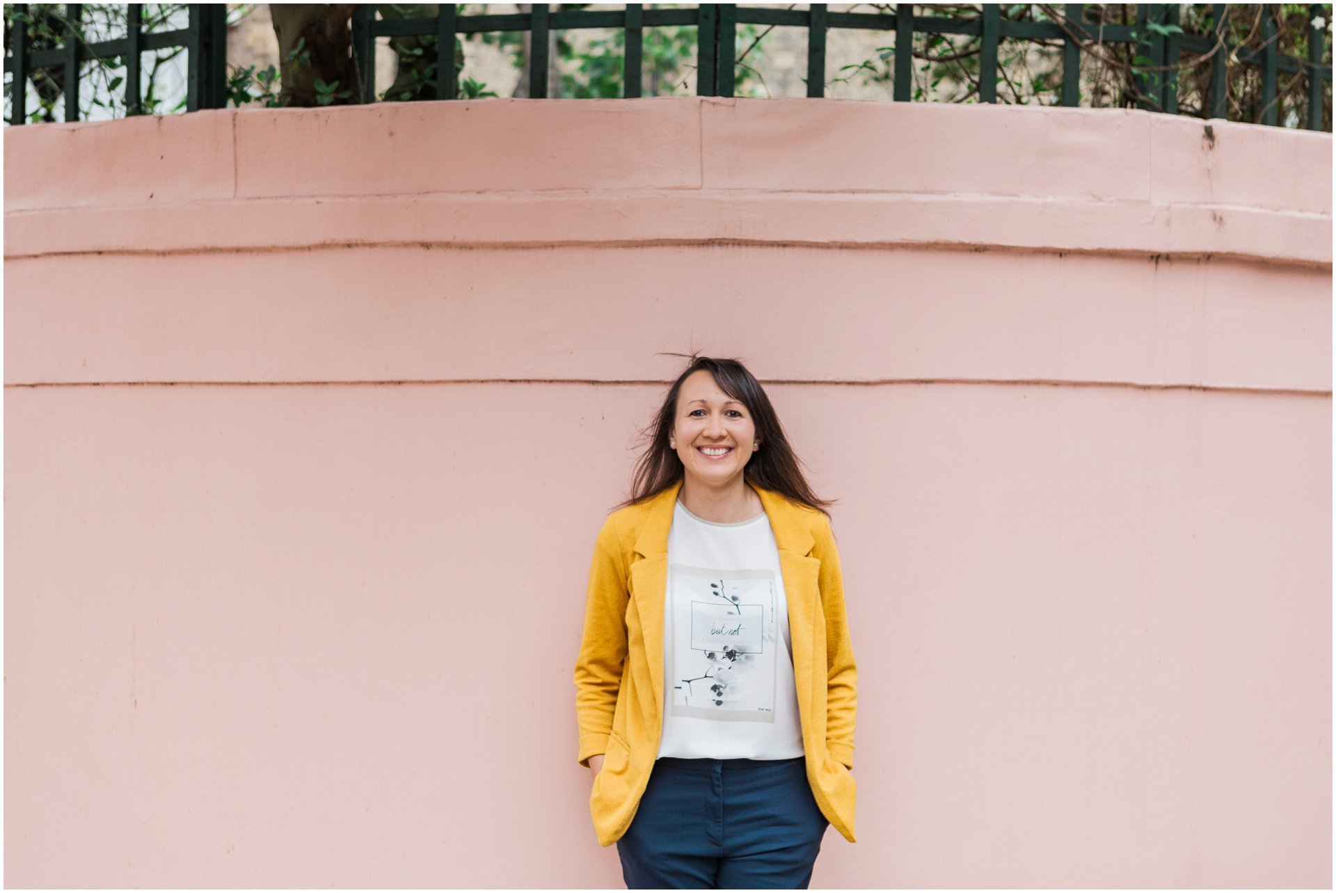 Female business coach in a yellow blazer against a pink wall in Chelsea. Images by London brand photographer AKP Branding Stories