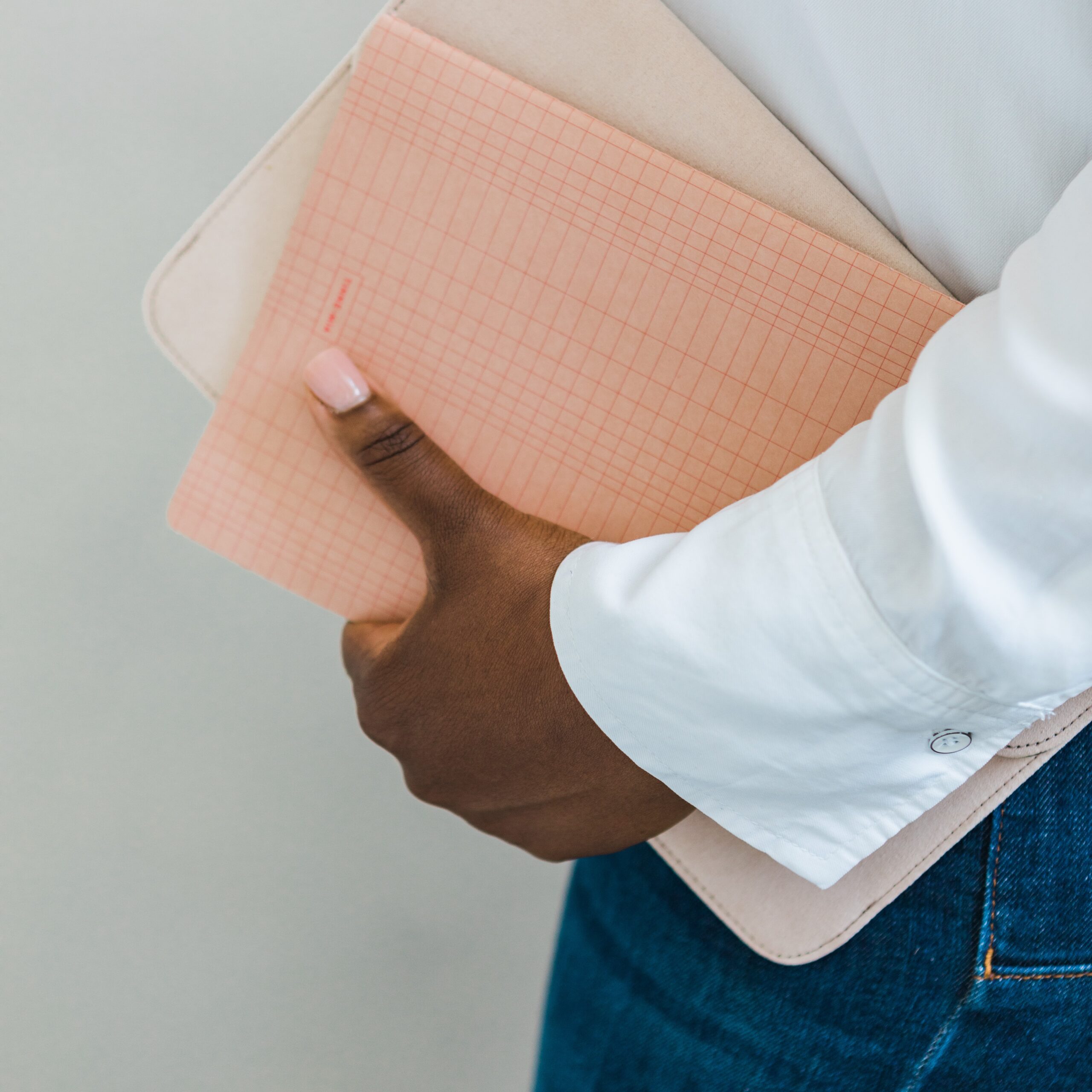 A close up image of a pink notebook being held by a black lady in a white shirt and blue jeans Image taken by London Brand Photographer for the blog post The Power of Inclusivity in Brand Photography: Representation Matters